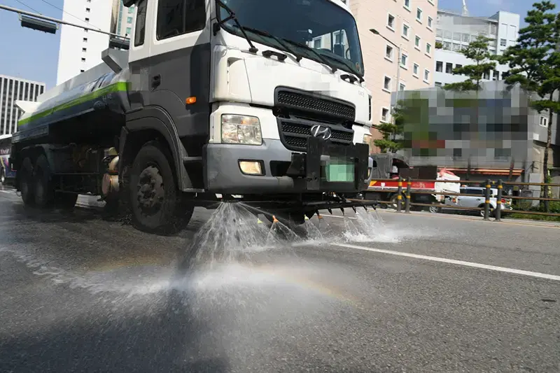 대형 살수차 뒤쪽 살수봉에서 물이 쏟아져 도로가 젖어 있는 모습