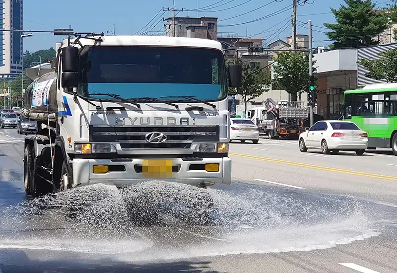 차가 다니는 시내 도로에서 살수차가 물을 뿌리며 주행하는 모습